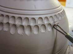 a person using a pair of pliers to work on a large vase with holes in it