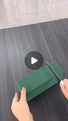 a person cutting up a piece of green material with scissors on the floor next to it