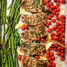 salmon, asparagus and tomatoes on a sheet of foil with lemon wedges