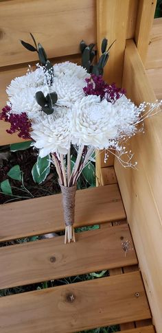 a bouquet of flowers sitting on top of a wooden bench