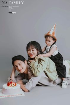 a woman and two children sitting on top of each other with a cake in front of them