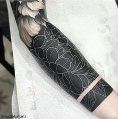 a black and white tattoo with flowers on it's arm, sitting on a table