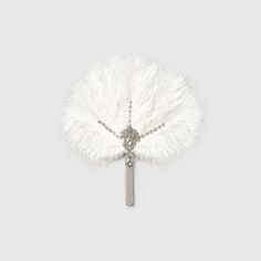 a white feather fan with a tassel hanging from it's center point on a chain