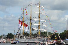 a large boat with lots of flags on it in the water next to other boats