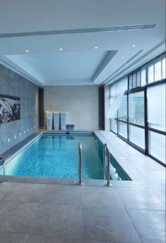 an indoor swimming pool in a large building with glass doors and windows on both sides