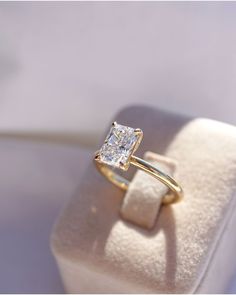 an engagement ring with a princess cut diamond on it's side in a box