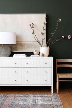 a white dresser sitting next to a wooden chair