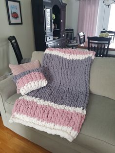 a couch with two pillows on it and a blanket draped over the back of it