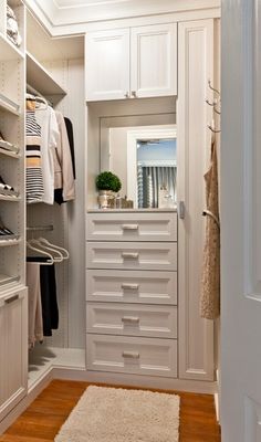 a walk in closet with white cabinets and drawers