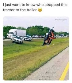 a tractor that is laying down in the grass next to a road with cars behind it