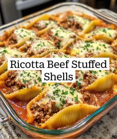 a glass casserole dish filled with stuffed shells and meat sauce, topped with parsley