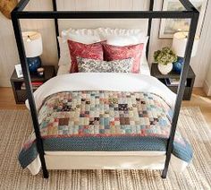 a four poster bed with colorful pillows and blankets