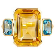 This 18 Karat Gold 7.79 Carat Blue & Yellow Topaz ""Three Stone"" Ring embodies an exquisite symphony of elegance and vibrancy. It’s a splendid testament to the seamless fusion of the serene blue and radiant yellow topaz stones. Crafted meticulously to exude luxury, this ring is a work of art that captures attention with its mesmerizing design. The ring showcases three resplendent topaz stones—a central enchanting blue topaz, flanked by two vivid yellow topaz gemstones. The striking contrast bet Three Stone Ring, Topaz Stone, Stone Design, Three Stone Rings, Yellow Sapphire, Topaz Gemstone, Blue And Yellow, Three Stone, Stone Ring