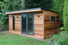 a small wooden shed sitting in the middle of a lush green yard next to trees