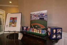 a table with pictures and baseball memorabilia on it in front of a wall mounted photo