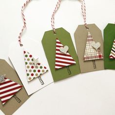 four tags with christmas trees on them are hanging from twine string and decorated with red, white and green paper