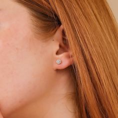 a close up of a person with red hair wearing a pair of ear studs