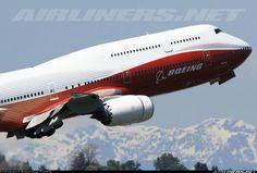 a large jetliner flying through the air with mountains in the background