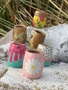 five painted pots sitting on top of a rock