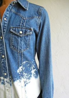 a blue jean jacket with white paint splattered on it