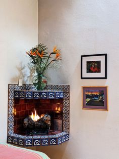 a fire place in the corner of a room with pictures on the wall above it