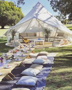 a tent set up in the middle of a field with lots of pillows on it