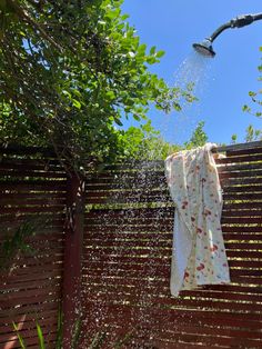 a shower head spewing water onto a towel hanging on a fence