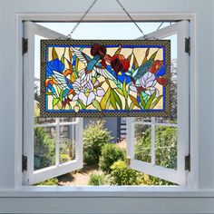 an open window with a stained glass flower design hanging from it's side wall