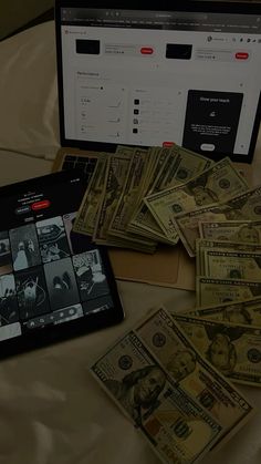 a laptop computer sitting on top of a bed covered in money