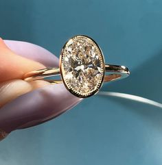 a close up of a person's hand holding a ring with a diamond in it