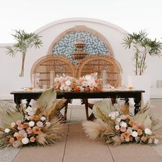 an outdoor table set up with flowers and greenery