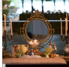 a table topped with candles and figurines next to a mirror