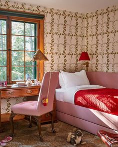 a bedroom with pink furniture and wallpaper on the walls, along with a red chair