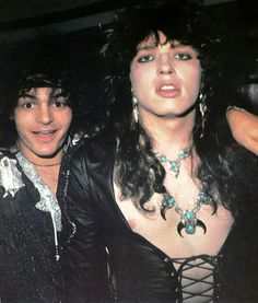 two women are posing for the camera with one woman wearing a leather jacket and necklace