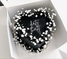 a heart shaped cake in a box with white flowers on it that says date happy