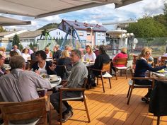 many people are sitting at tables on the deck