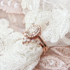 two wedding rings sitting on top of a white lace covered piece of cloth with lacy material in the background