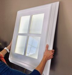 a woman is painting a window with white paint