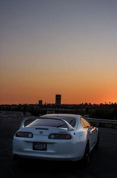 a white car parked in a parking lot at sunset