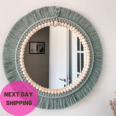 a round mirror hanging on the wall next to a pink sign that says next day shipping