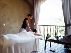 a woman getting a back massage from a man in a room with a large window