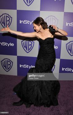 a woman in a black dress poses on the purple carpet at an instyle event