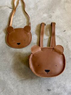 a brown bear shaped purse sitting on top of a floor next to a small bag