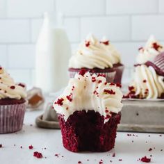 red velvet cupcakes with white frosting and sprinkles on a tray