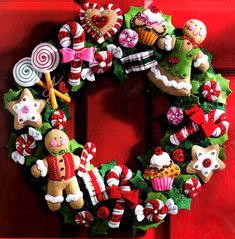 a christmas wreath is hanging on a red door with candy canes and candies