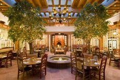 an indoor dining area with tables, chairs and chandelier in front of a fountain