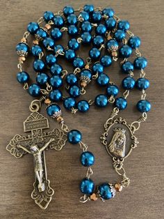 "This beautiful handmade rosary is made with 8mm blue glass pearls, bronze beads cap and 2\" Pardon crucifix. Length: 20\" inches long" Blue Rosary With 8mm Beads And Crucifix, Blue Rosary With 8mm Beads In Cross Shape, Adjustable Blue Rosary With Miraculous Medal, Paracord Rosary, Handmade Rosary, Bead Rosary, Immaculate Heart Of Mary, Heart Of Mary, Immaculate Heart