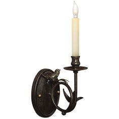 a candle is lit on the wall next to a light fixture with an iron frame