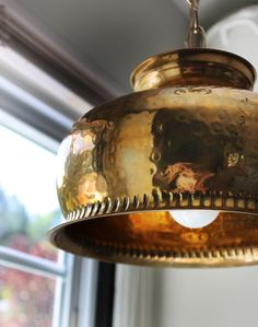 an old fashioned light hanging from a ceiling in a room with a large window behind it