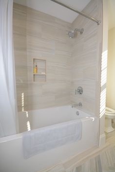 a bathroom with a tub, toilet and shower curtain